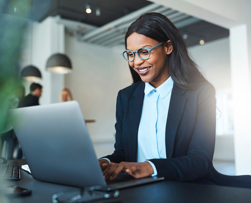 Smiling African American Businesswoman Using A Laptop At Her Desk