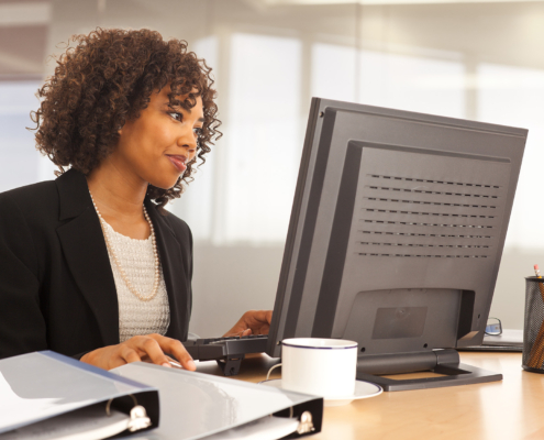 Young Businesswoman Using Computer At Desk Indoors Office Building